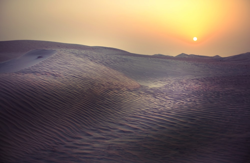 the sun is setting over the sand dunes