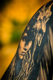 A cinematic portrait tattoo showcasing lifelike detail and depth on charcoal skin tone.