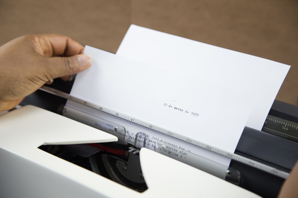 pessoa segurando papel branco da impressora