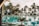 A tranquil resort setting with a large, inviting swimming pool surrounded by palm trees. In the background, lounge chairs and umbrellas are neatly arranged, creating a relaxing atmosphere. The reflection of the palm trees in the water enhances the serene ambiance.