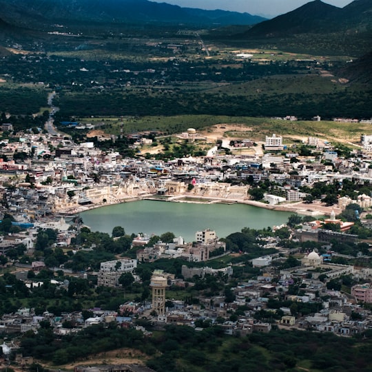 body of water between buildings during daytime in Pushkar Lake India