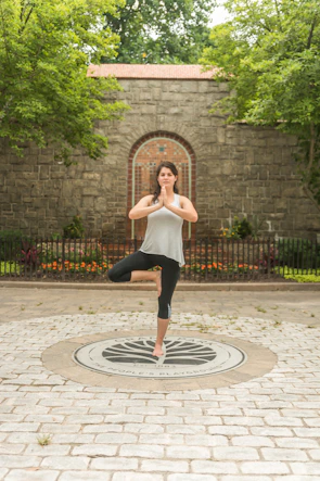 A fit young woman practicing yoga outdoors surrounded by lush greenery.