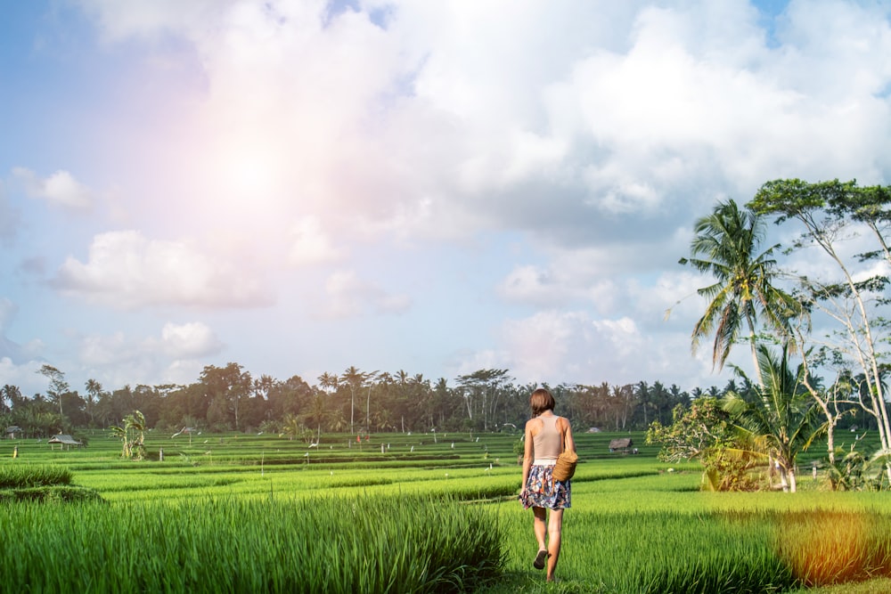 woman walking on green grass pathway