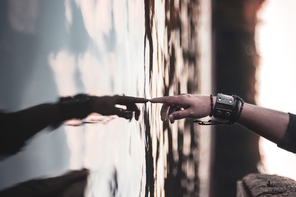 selective focus photography of person's touching body of water