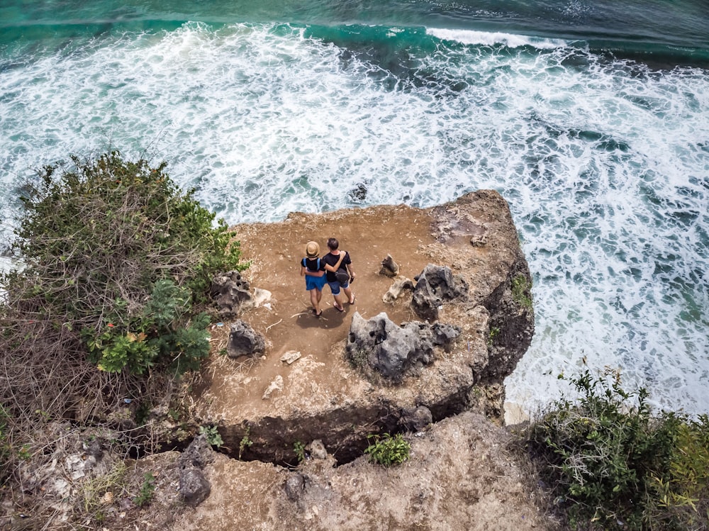 two person standing near the cliff