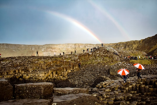 two person holding umbrella in front of hill in Giant's Causeway United Kingdom