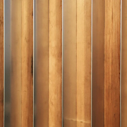 Vertical wooden planks with a natural finish are aligned in a parallel pattern. The wood has visible grain and variation in shades, creating a textured appearance. The planks are evenly spaced and have a warm, earthy tone.