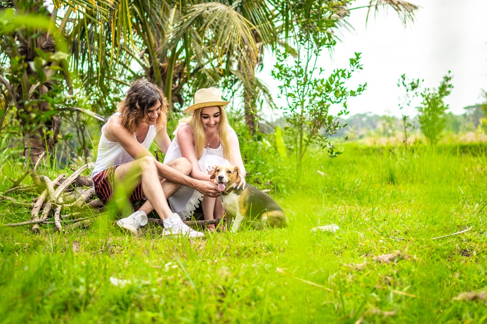 man and woman holding black dog sitting on green grass field