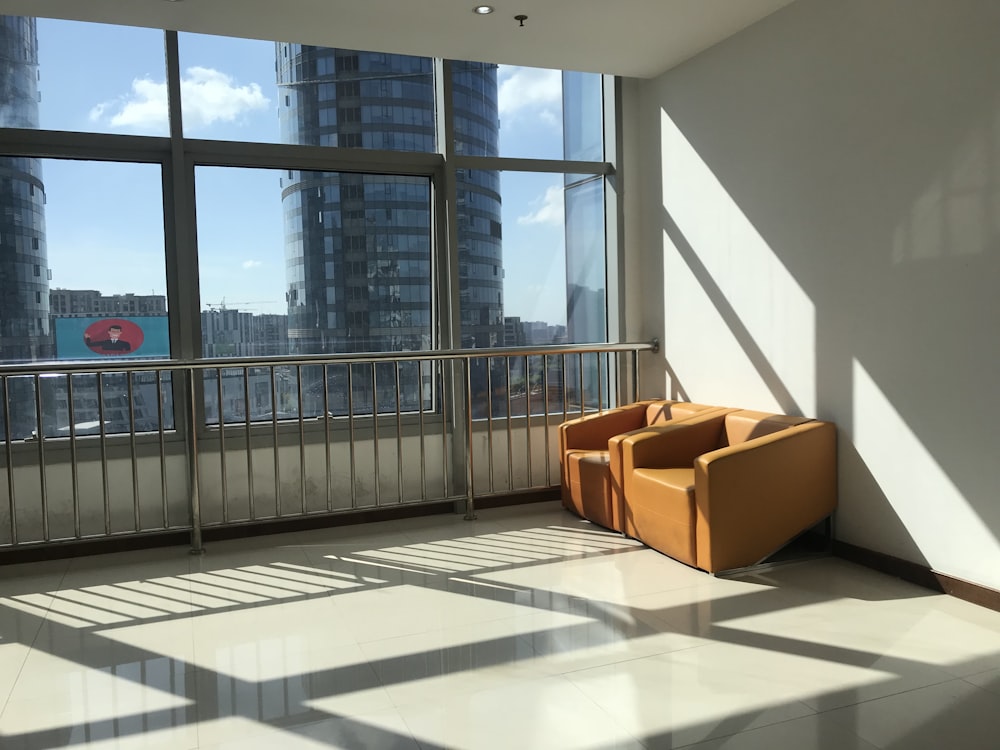 two brown leather sofa chairs beside grey metal railings