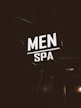 A brightly illuminated sign featuring the words 'MEN SPA' is displayed in a dark, industrial-looking environment. The sign stands out in contrast to the dim surroundings, providing a focus point against the otherwise shadowy backdrop.