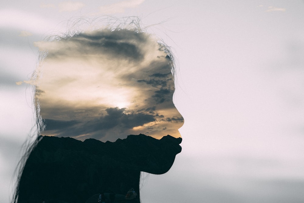 a silhouette of a person with a cloudy sky in the background