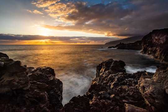 black rock formation beside body of water at golden hour in La Palma Spain