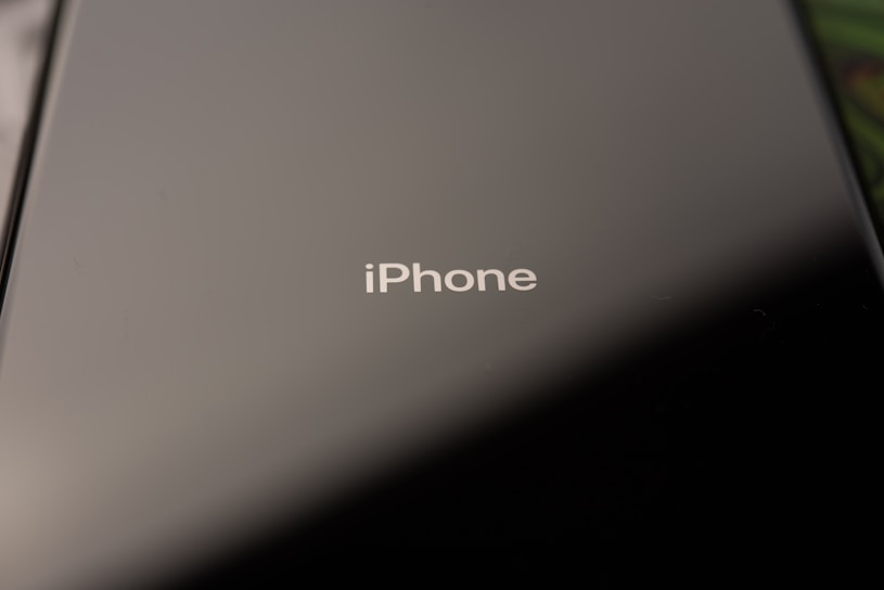 Close-up of a sleek iPhone with a shimmering imported accessory beside it on a wooden table.