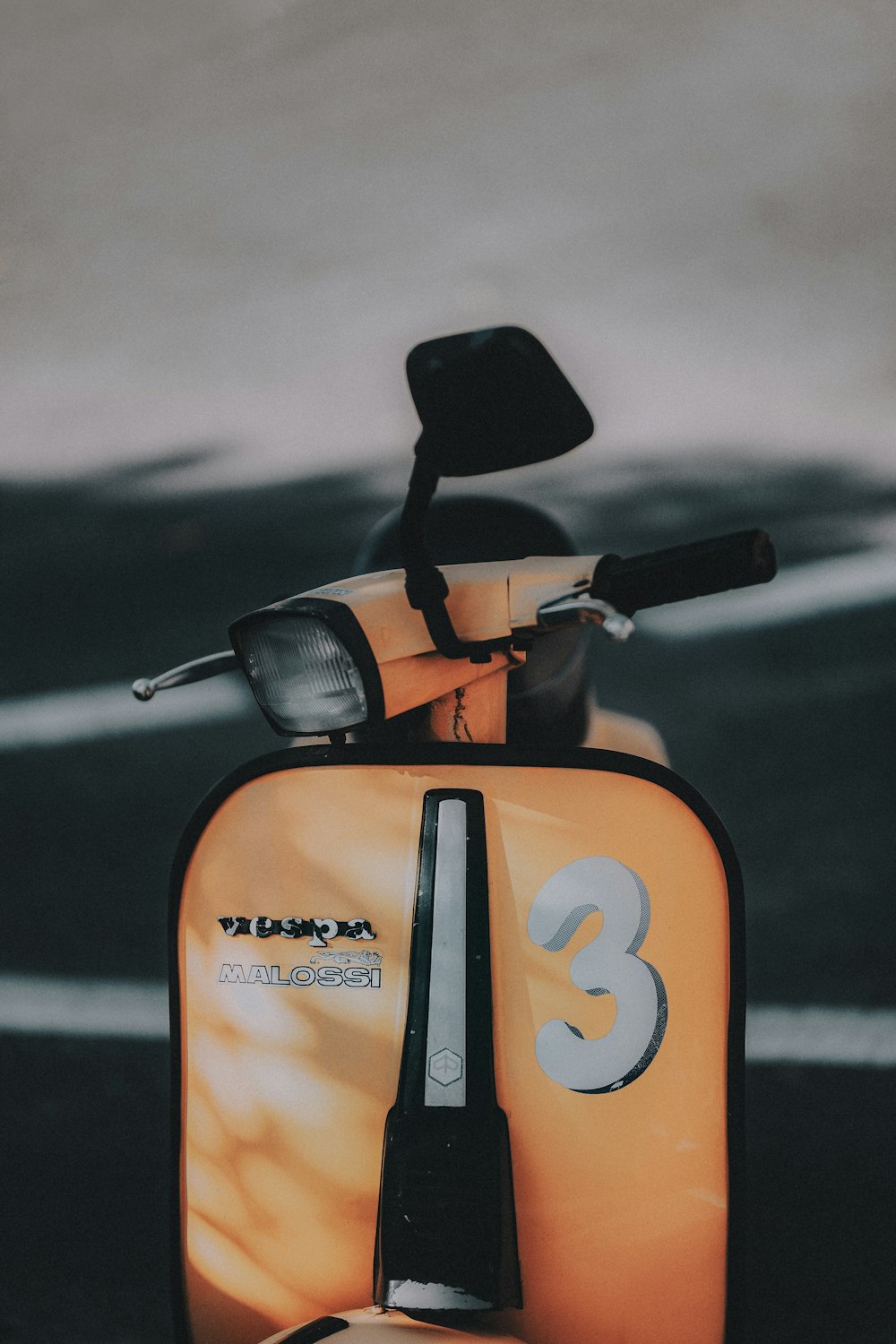 orange Malossi motor scooter parked on pavement selective focus photo