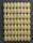 A grid of oval-shaped, textured tablets is neatly arranged on a dark background, each exhibiting a slightly speckled pattern.