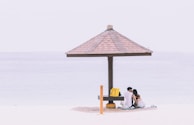 A couple relaxing under a beach umbrella.