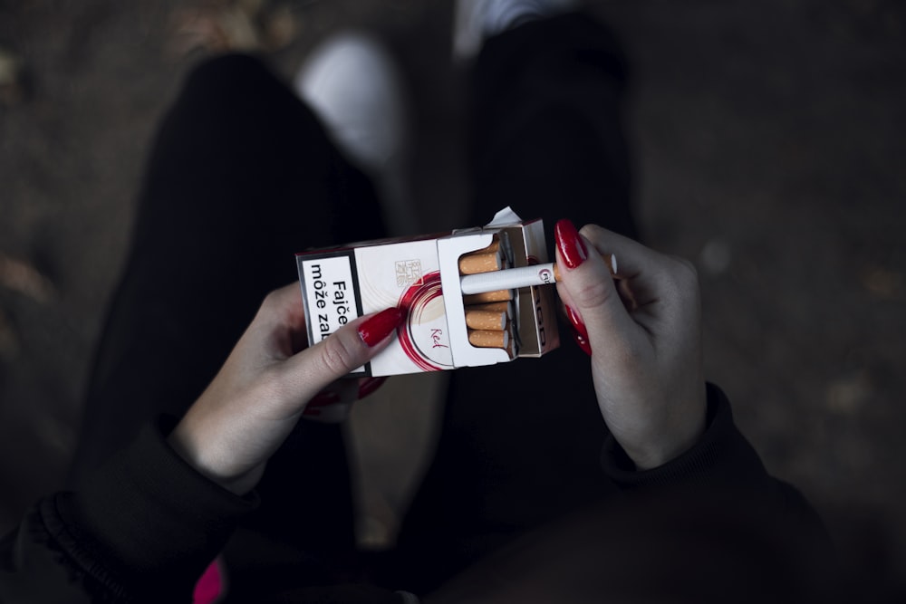 person holding cigarette out of the pack