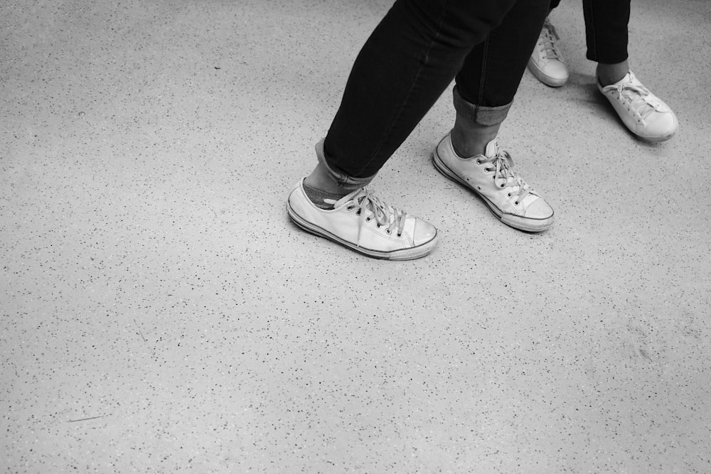 grayscale photography of person wearing low-top sneakers