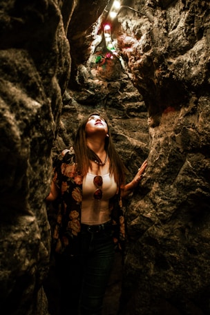 woman looking up while standing inside cave