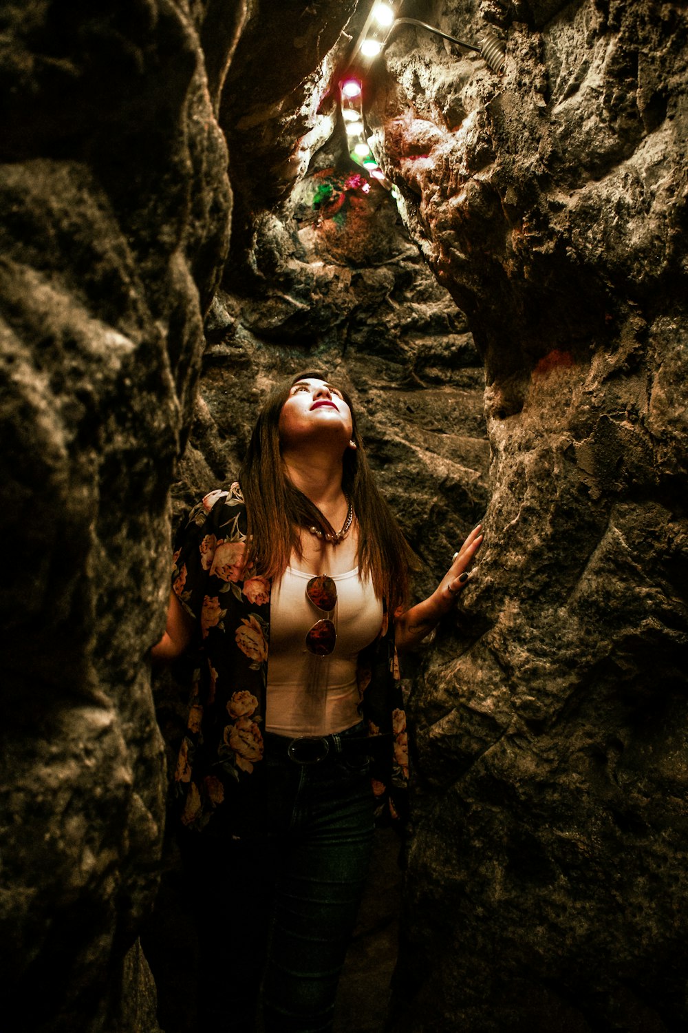 woman looking up while standing inside cave