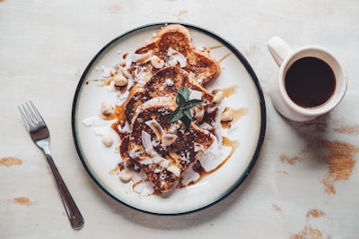 A plate of French toast drizzled with syrup and sprinkled with nuts.