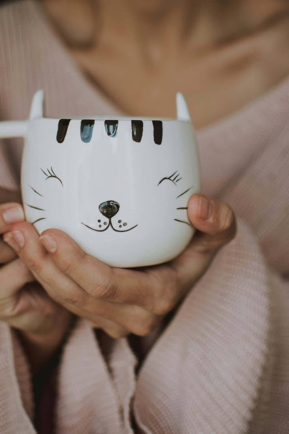 person holding white and black cat graphic teacup