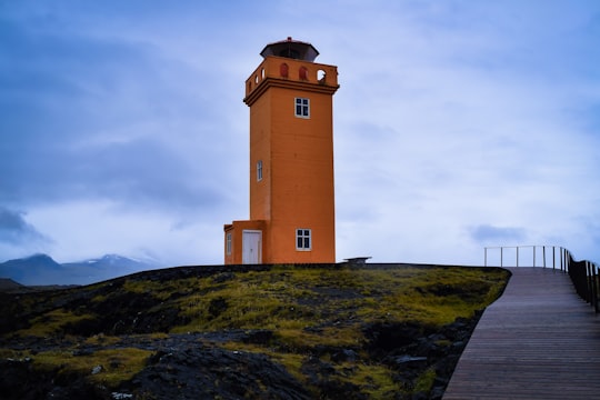 orange concrete building under blue sky in Svörtuloft Lighthouse Iceland
