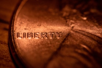 Close-up view of a coin with the word 'LIBERTY' prominently displayed in the center, showcasing the intricate details and texture of the metal surface.