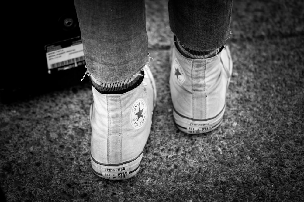 grayscale photography of person wearing Converse All-Star high-top sneakers