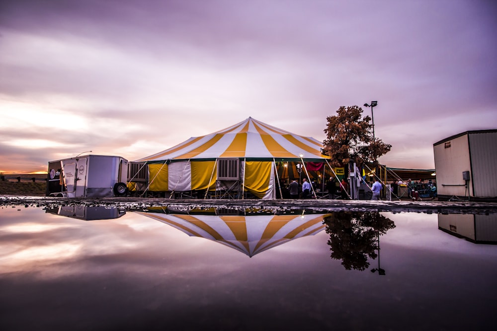 white and yellow striped carnival tent near body of water