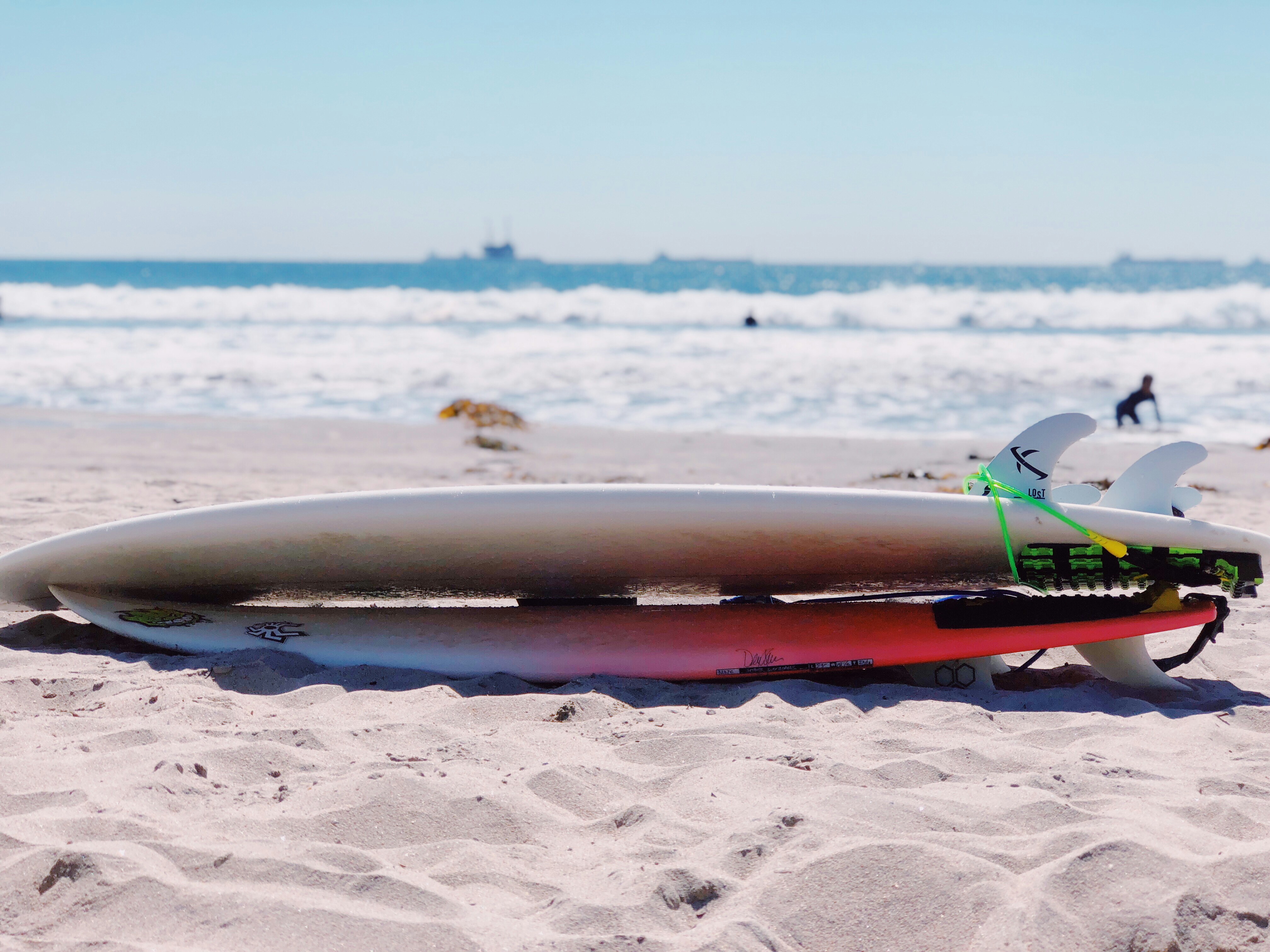 white and red 2 tail surfboard on seashore