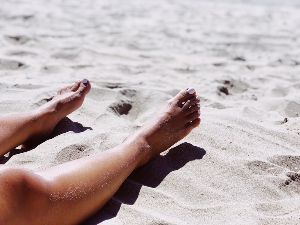 person's legs on gray sand during daytime