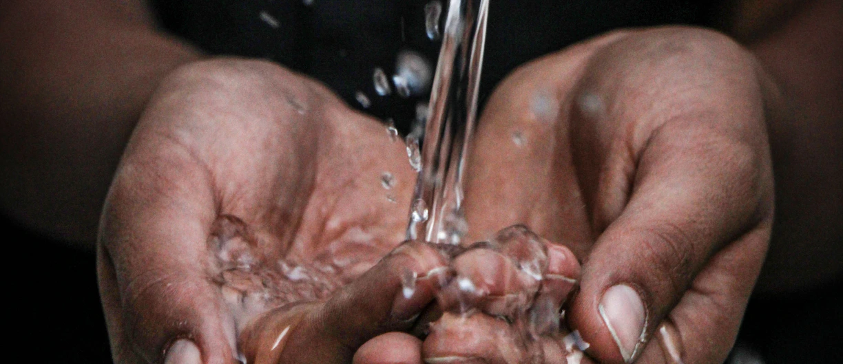 pouring water on person's hands