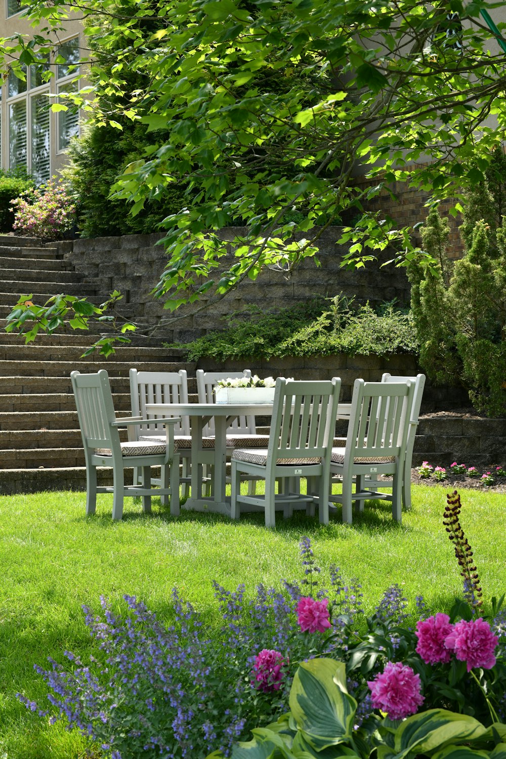 白い木製のダイニングテーブルと芝生の上に椅子が置かれています