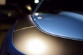 Close-up of a sleek black car hood reflecting soft studio lights.