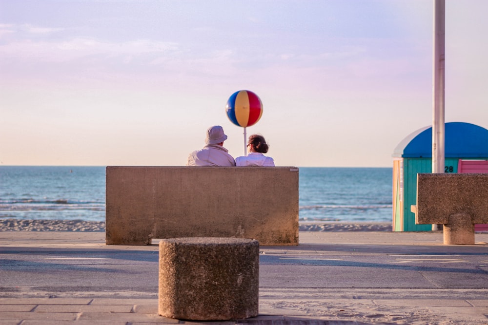 zwei Personen sitzen tagsüber auf einer Bank in der Nähe des Meeres