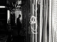 A city alley at night bathed in shadows with a figure clad in an electric red-glowing jacket blending into the dark environment.