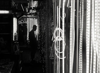 A city alley at night bathed in shadows with a figure clad in an electric red-glowing jacket blending into the dark environment.