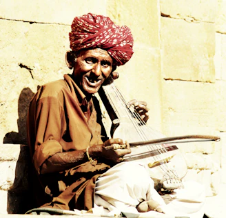 An elder playing the tembûr, the soulful Kurdish string instrument, in a sunlit room.