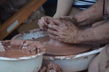 Students smiling and working together around a large pottery table.