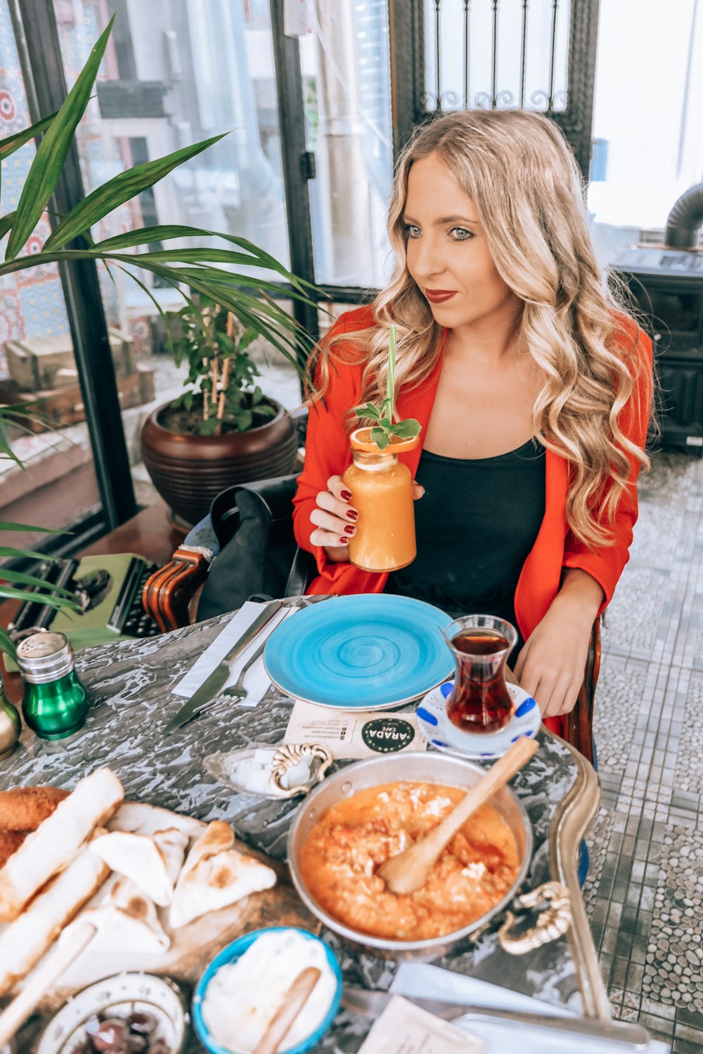 woman sits near chair holding orange drink