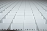 A close-up view of a grid-like arrangement of white plastic squares, creating a repetitive geometric pattern. The squares appear to be part of a larger structure, possibly a partition or organizer.