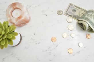 scattered coins and a $50 and $1 bills on a marble countertop