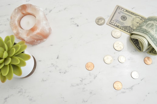 scattered coins and a $50 and $1 bills on a marble countertop