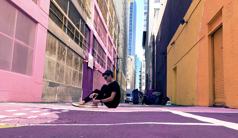 man sitting on ground near building