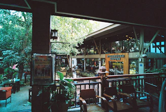 Cozy coffee shop patio with seating and lush greenery around.
