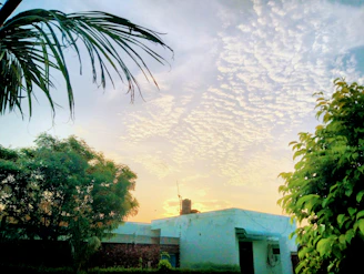 A serene villa surrounded by lush tropical greenery under a soft pale purple sky at sunset.