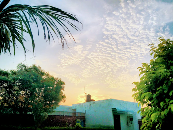 A serene villa surrounded by lush tropical greenery under a soft pale purple sky at sunset.