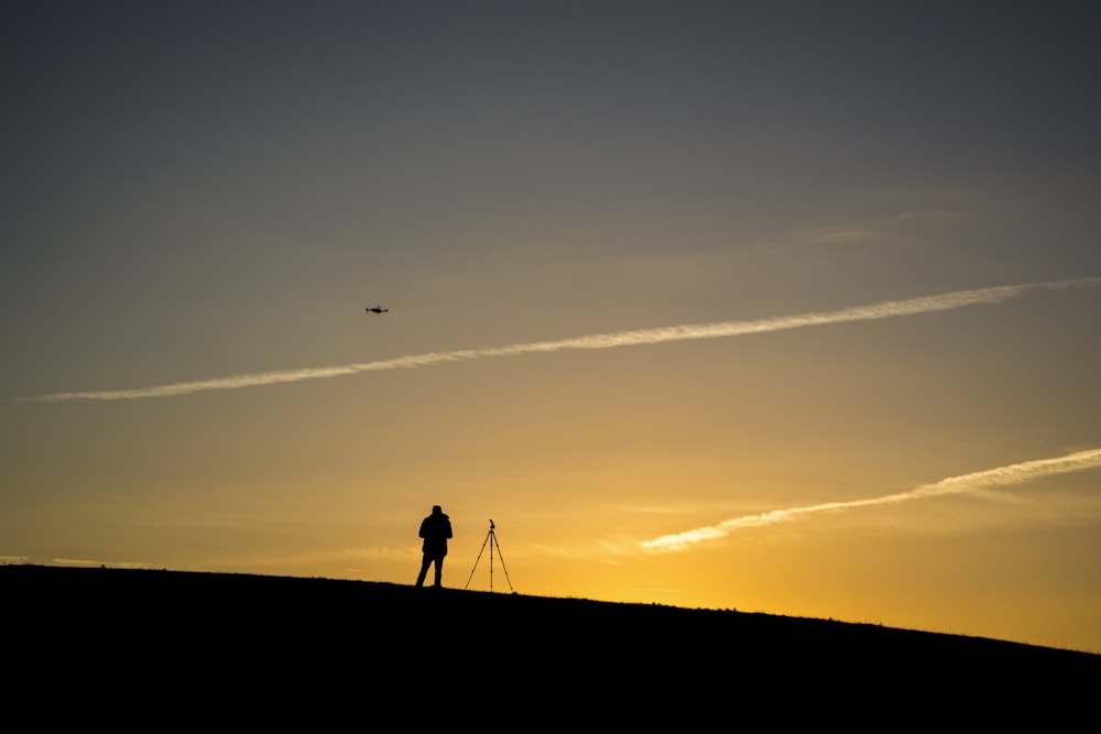 silhouette of person beside tripod