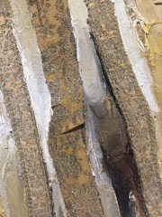 Close-up of an encaustic wax painting showcasing textured layers of natural earth tones inspired by Oregon's river landscapes.